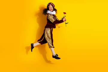 Young nobleman in medieval costume holding rose on vibrant yellow background, epitomizing classic...