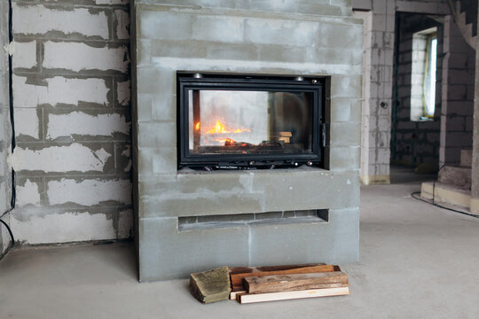 Fire burning in freshly installed fireplace in newly built house. Repair of new home after construction.