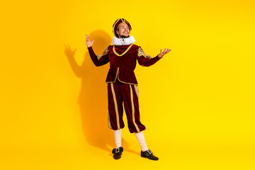 Obraz premium Portrait of a man in historic noble attire standing confidently on a vibrant yellow background, expressing theatrical elegance and charm