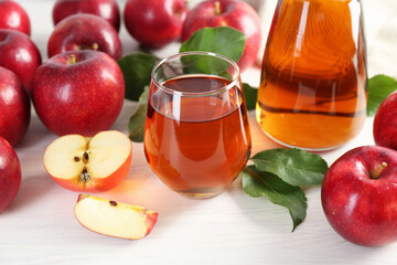 Fresh apple juice, fruits and green leaves on white wooden table