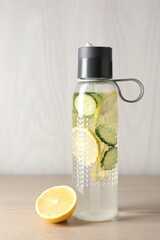 Lemon water with cucumber in bottle on wooden table