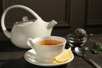 Refreshing green tea in cup and slice of lemon on dark textured table