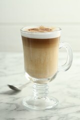 Tasty latte macchiato in glass cup on white marble table, closeup