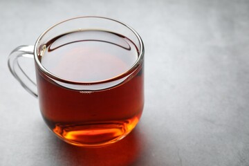 Refreshing black tea in cup on grey table, closeup. Space for text