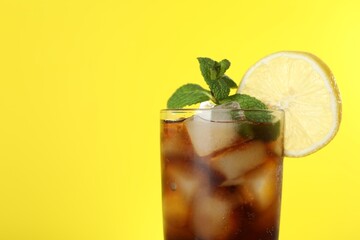 Fototapeta premium Refreshing iced cola with mint and lemon on yellow background, closeup. Space for text