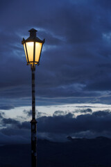 Glowing street lamp against dark clouds