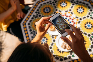 University student taking pictures of moroccan food with smartphone