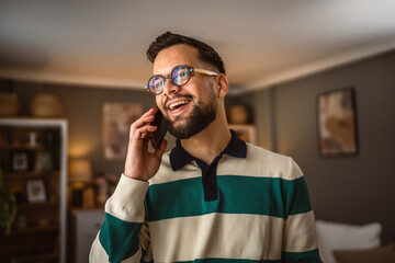 portrait of adult man stand and talk on mobile phone at home