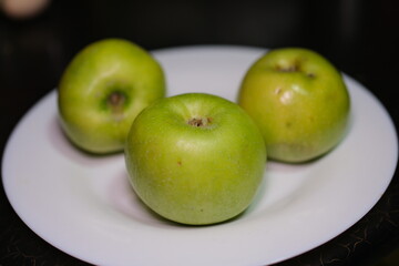 Plate with fresh green apples over green background. Flat lay with copy space. High quality photo