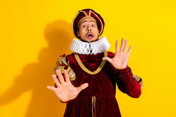 Young man in colorful nobleman costume posing dramatically against yellow background