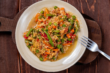 Couscous with vegetables in sauce on a plate on the table next to a fork