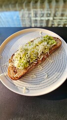 Smashed avocado sandwich on toasted bread with grated cheese