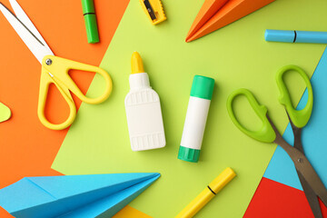 Flat lay composition with glue, scissors and other stationery on color background