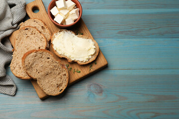 Fresh bread with butter on blue wooden table, flat lay. Space for text