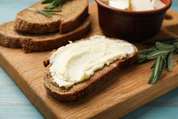 Fresh bread with butter and rosemary on blue wooden table, closeup