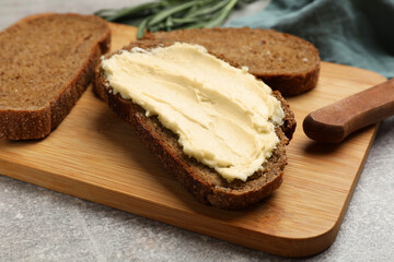 Fresh bread with butter and knife on grey table, closeup