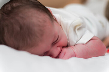7 day old newborn, close up face photo of baby lying in bed