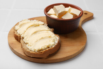 Fresh bread with butter on white tiled table, closeup