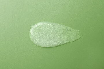 Smear of body scrub on green background, top view