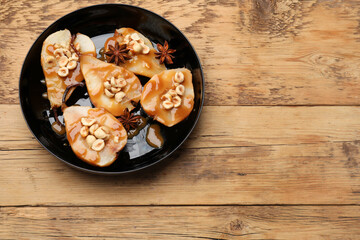 Delicious pears with caramel sauce, nuts and anise stars on wooden table, top view. Space for text