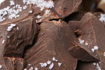 Pieces of tasty chocolate with salt on table, closeup