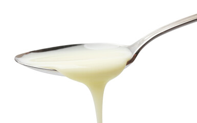Delicious condensed milk pouring from spoon isolated on white