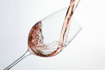 Pouring rose wine into glass on white background