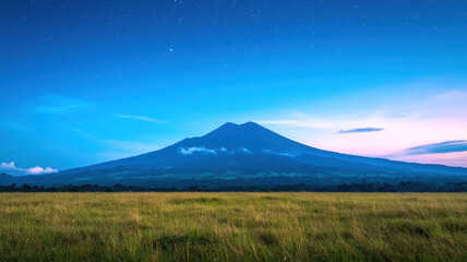 Obraz premium A serene landscape featuring a majestic mountain under a twilight sky, surrounded by lush green fields and scattered clouds.