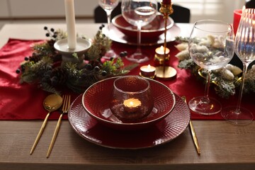 Christmas place setting with festive decor on wooden table in room