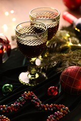 Glasses with red wine and beautiful Christmas decor on table, closeup