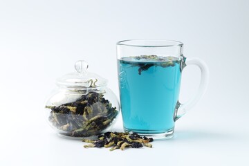 Fresh butterfly pea flower tea and dry petals on white table, closeup