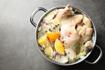 Whole turkey, cut citrus fruits and spices in pot on grey textured table, top view. Space for text