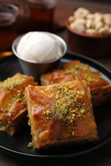 Delicious baklava with crushed nuts and ice cream on table, closeup