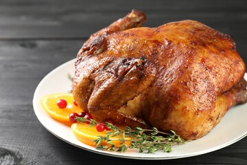 Delicious baked turkey, orange slices, cranberries and thyme on gray wooden table, closeup