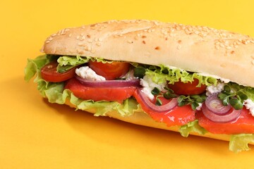 Delicious baguette with salmon on yellow background, closeup