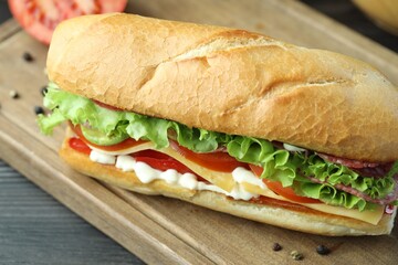 Delicious baguette sandwich with salami and cheese on table, closeup