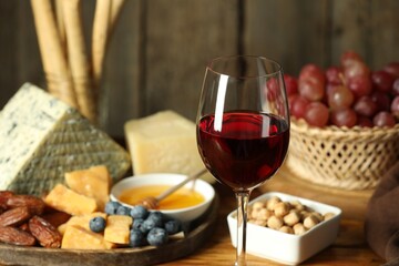 Red wine and different snacks served on table, closeup