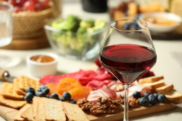 Red wine and different snacks served on table, closeup