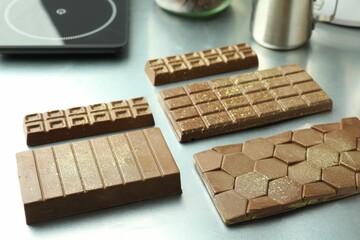 Different tasty Dubai chocolate bars with pistachios and knafeh on grey table