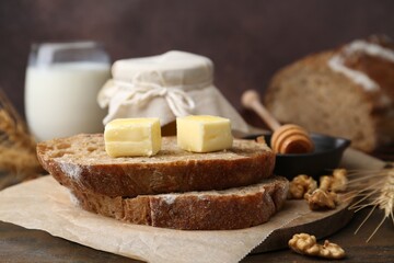 Slices of bread with butter, honey and walnuts on wooden table, closeup