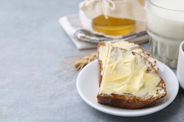 Slices of bread with butter, honey and milk on light grey table, closeup. Space for text