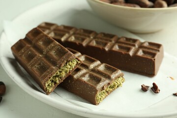 Tasty Dubai chocolate bars with pistachios and knafeh on light table, closeup