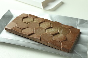 One tasty Dubai chocolate bar with pistachios and knafeh on white textured table, closeup