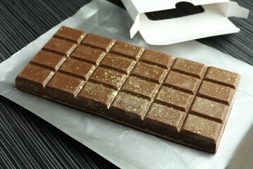 One tasty Dubai chocolate bar with pistachios and knafeh on black wooden table, closeup