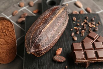 Cocoa pod, beans, powder and chocolate on grey table, closeup