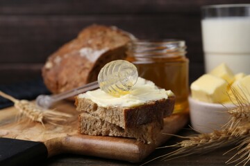 Tasty sandwich with butter, honey, dipper and milk on wooden table, closeup