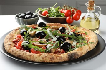 Tasty pizza with mushrooms, black olives, arugula and tomatoes on white table, closeup