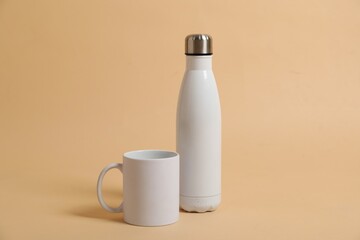 Blank mug and thermo bottle for branding on beige background. Mockup for design