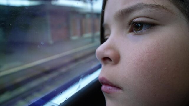 Thoughtful child close-up face leaning on train window staring at platform station arrival. Macro close-up of contemplative 8 year old little girl arriving at destination
