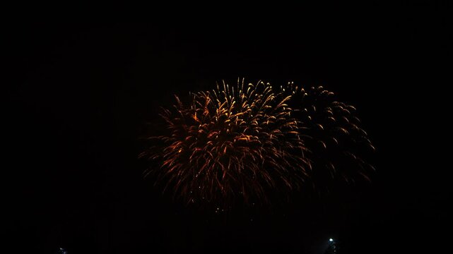 red and gold sparks scatter fireworks on the black night sky above the city. General plan